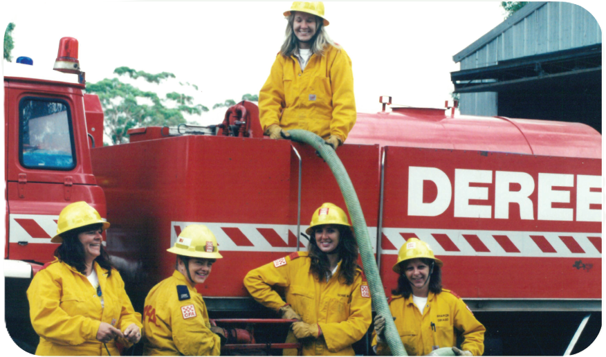 Female brigade members standing beside a red fire truck